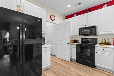 Kitchen featuring white cabinetry, light hardwood / wood-style floors, and black appliances