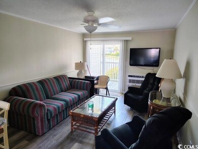 Living area with crown molding, wood finished floors, a textured ceiling, and ceiling fan. The walls have been spared for your placement of favorite pictures.