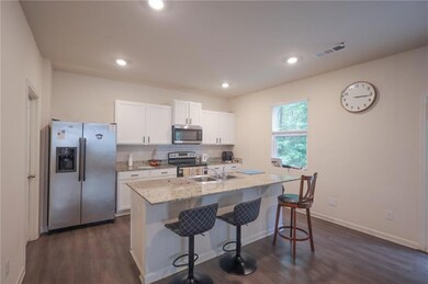 Kitchen with stainless steel appliances, white cabinets, a kitchen bar, decorative backsplash, and dark wood-type flooring