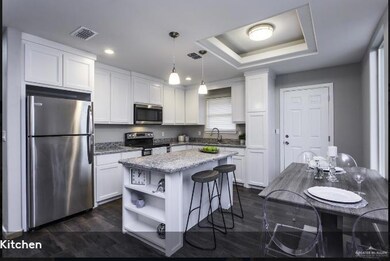 Kitchen with a kitchen island, white cabinetry, appliances with stainless steel finishes, and hanging light fixtures