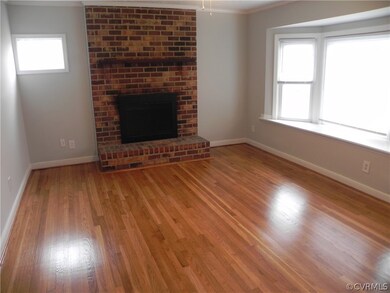 Unfurnished living room featuring ornamental molding, wood-type flooring, and a brick fireplace