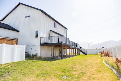 Back of property featuring a deck with mountain view, stairs, a fenced backyard, board and batten siding, and a patio