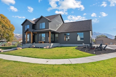 Modern inspired farmhouse with a mountain view, board and batten siding, a front yard, and roof with shingles