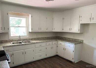Kitchen with a sink, dark wood-type flooring, whit