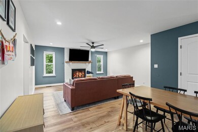 Living room featuring a brick fireplace, ceiling fan, light wood-style floors, and recessed lighting