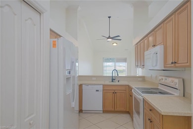 Kitchen with white appliances, a sink, a ceiling fan, light countertops, and light tile patterned floors