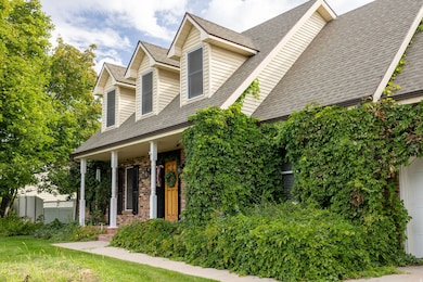 New england style home with roof with shingles, a porch, brick siding, a front lawn, and a garage