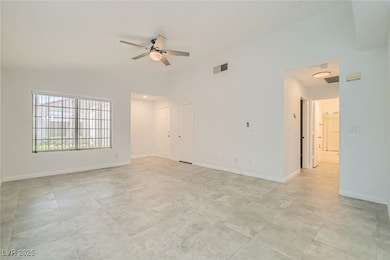 Empty room with a ceiling fan and vaulted ceiling