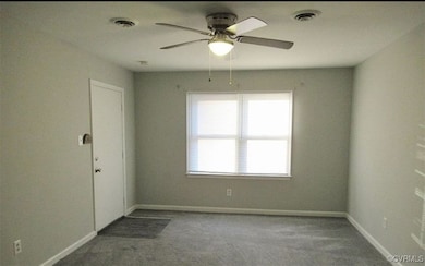Carpeted empty room with baseboards, a ceiling fan
