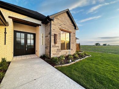 Property entrance featuring brick siding, a yard, french doors, and stone siding