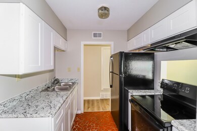 Kitchen with black appliances, white cabinetry, exhaust hood, and dark wood-type flooring