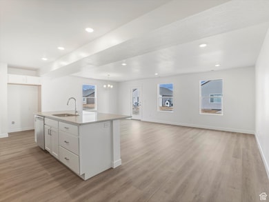 Kitchen with white cabinets, open floor plan, plenty of natural light, light wood-style flooring, and recessed lighting
