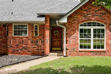 Doorway to property featuring roof with shingles, a lawn, and brick siding