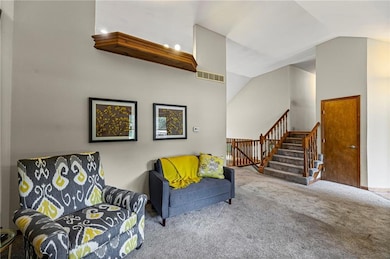 Living area featuring carpet flooring, stairs, and lofted ceiling