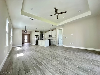 Unfurnished living room featuring a tray ceiling,