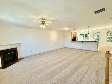 The freshly painted Family Room with lighted ceiling fan, cozy fireplace, new carpeting and view into Kitchen.