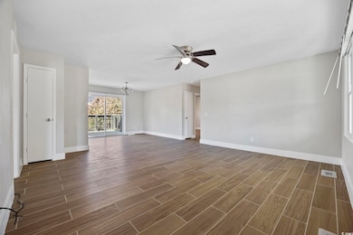 Empty room with a chandelier, wood tiled floors, and ceiling fan