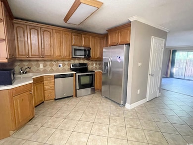 Kitchen featuring stainless steel appliances, a sink, decorative backsplash, light tile patterned flooring, and light countertops