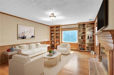 Living area featuring a fireplace, light wood-style flooring, and ornamental molding