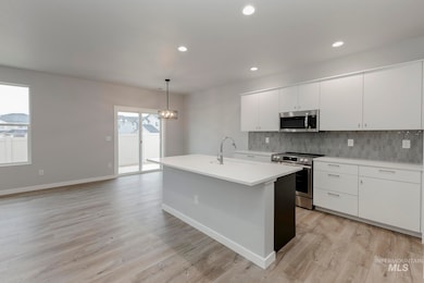 Kitchen with white cabinetry, appliances with stainless steel finishes, hanging light fixtures, decorative backsplash, and recessed lighting