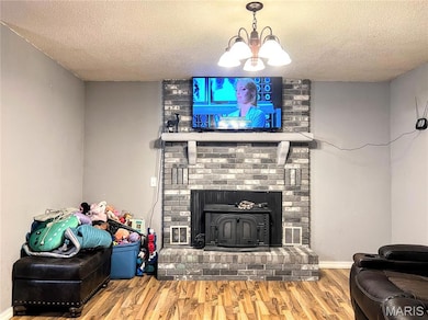 Living area with wood finished floors, a textured ceiling, and a wood stove