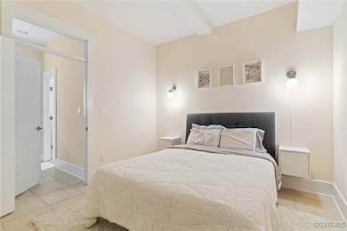 Bedroom with tile patterned flooring, beam ceiling