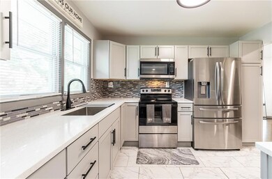 Kitchen featuring appliances with stainless steel finishes, sink, tasteful backsplash, and light tile flooring