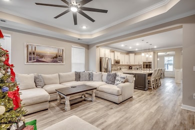 Living room with ceiling fan, a raised ceiling, or