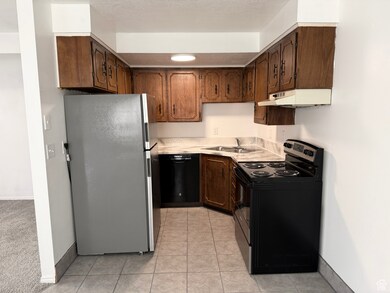 Kitchen with stainless steel appliances, light countertops, light tile patterned floors, and under cabinet range hood