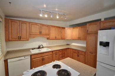 Kitchen with white appliances, lofted ceiling, and track lighting