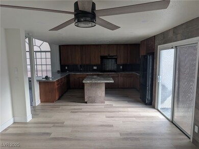 Kitchen with a kitchen island, tasteful backsplash, black appliances, light wood-style flooring, and dark stone countertops