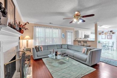 Living area with a textured ceiling, ceiling fan, ornamental molding, hardwood / wood-style flooring, and plenty of natural light