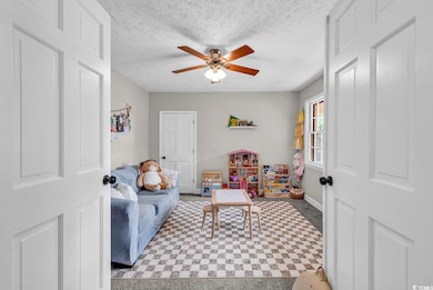 Living area featuring tile patterned floors, a ceiling fan, a textured ceiling, and baseboards