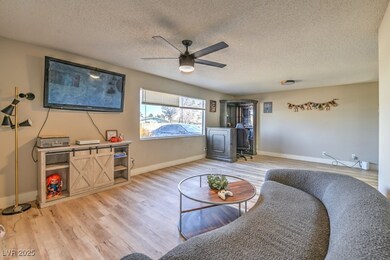 Living area with ceiling fan, baseboards, a textur
