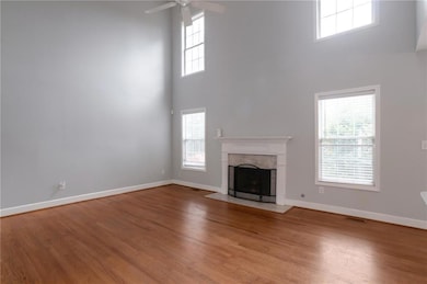 Unfurnished living room featuring a high ceiling, plenty of natural light, a ceiling fan, and baseboards
