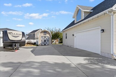 View of property exterior featuring roof with shingles, a garage, concrete driveway, and a storage unit