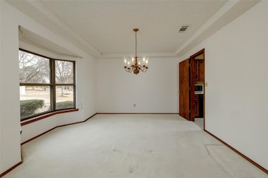 Empty room featuring light carpet, visible vents, 