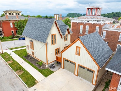 View of front of property featuring roof with shingles, board and batten siding, and driveway