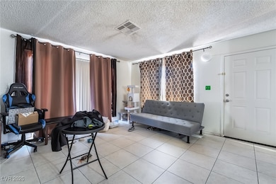 Living area featuring a textured ceiling and light tile patterned floors
