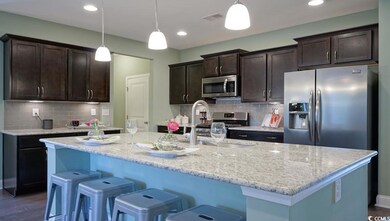 Kitchen featuring appliances with stainless steel finishes, dark brown cabinets, a center island with sink, a sink, and tasteful backsplash