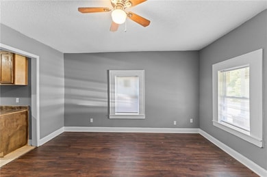 Spare room with dark wood finished floors, a textured ceiling, and a ceiling fan