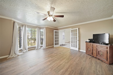 Spacious living area with large windows providing natural light and access to the adjacent room through French doors.
