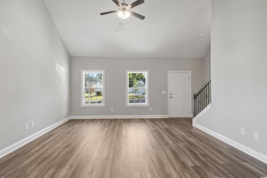 Unfurnished living room featuring ceiling fan and dark wood-type flooring