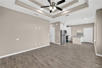 Unfurnished living room with a tray ceiling, ceiling fan, wood finished floors, and recessed lighting