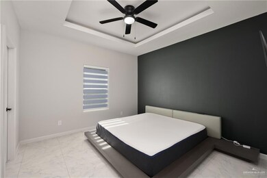 Bedroom with a tray ceiling, light marble finish flooring, and a ceiling fan