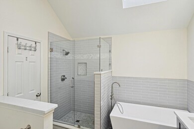 Bathroom featuring shower with separate bathtub and vaulted ceiling with skylight