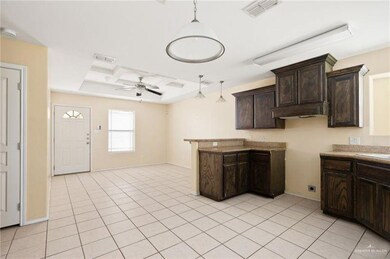 Kitchen with hanging light fixtures, dark brown cabinets, visible vents, and ceiling fan