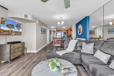 Living room with wood finished floors, baseboards, and a chandelier