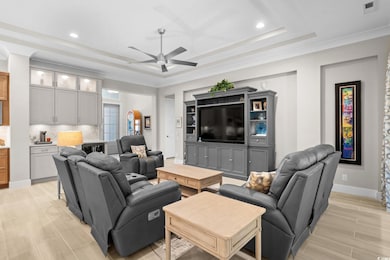 Living room with a raised ceiling, ceiling fan, wood tiled floors, and recessed lighting