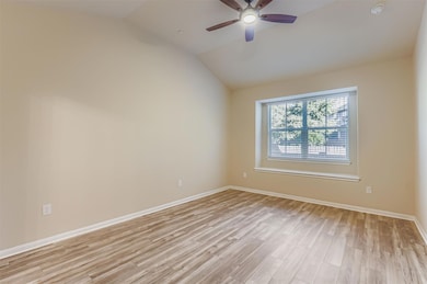 Unfurnished room with vaulted ceiling, light wood finished floors, and a ceiling fan